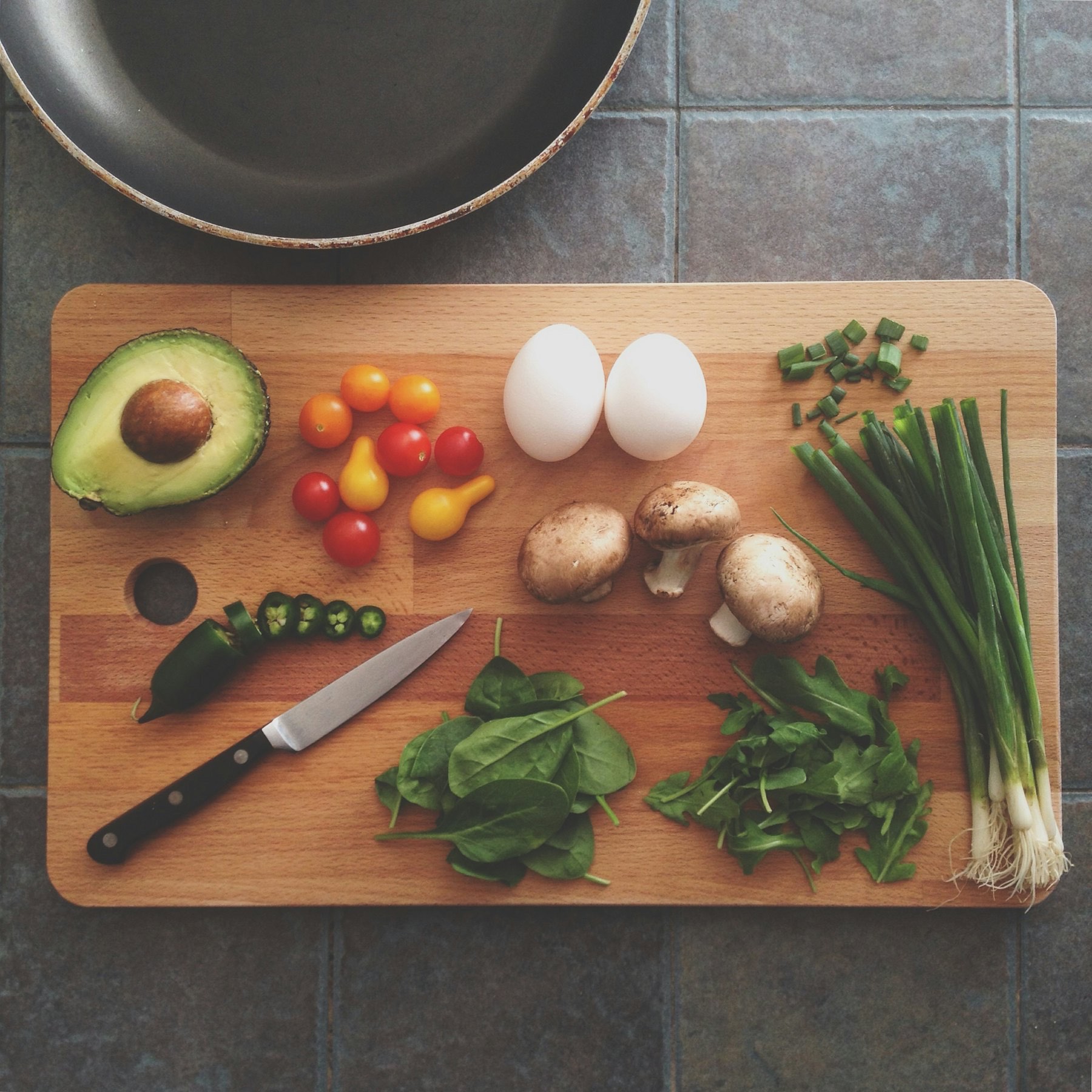 Fresh ingredients laid out on a cutting board beside a pan